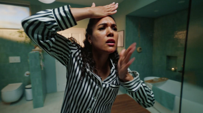 a woman standing in a bathroom holding her hands up to her head