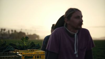 a man standing in a field next to a yellow crate