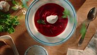 a bowl of red soup with sour cream on top