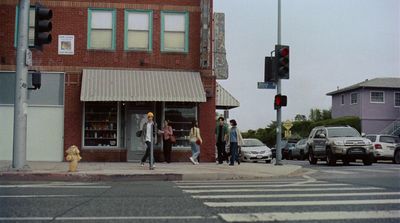 a group of people walking across a street next to a traffic light