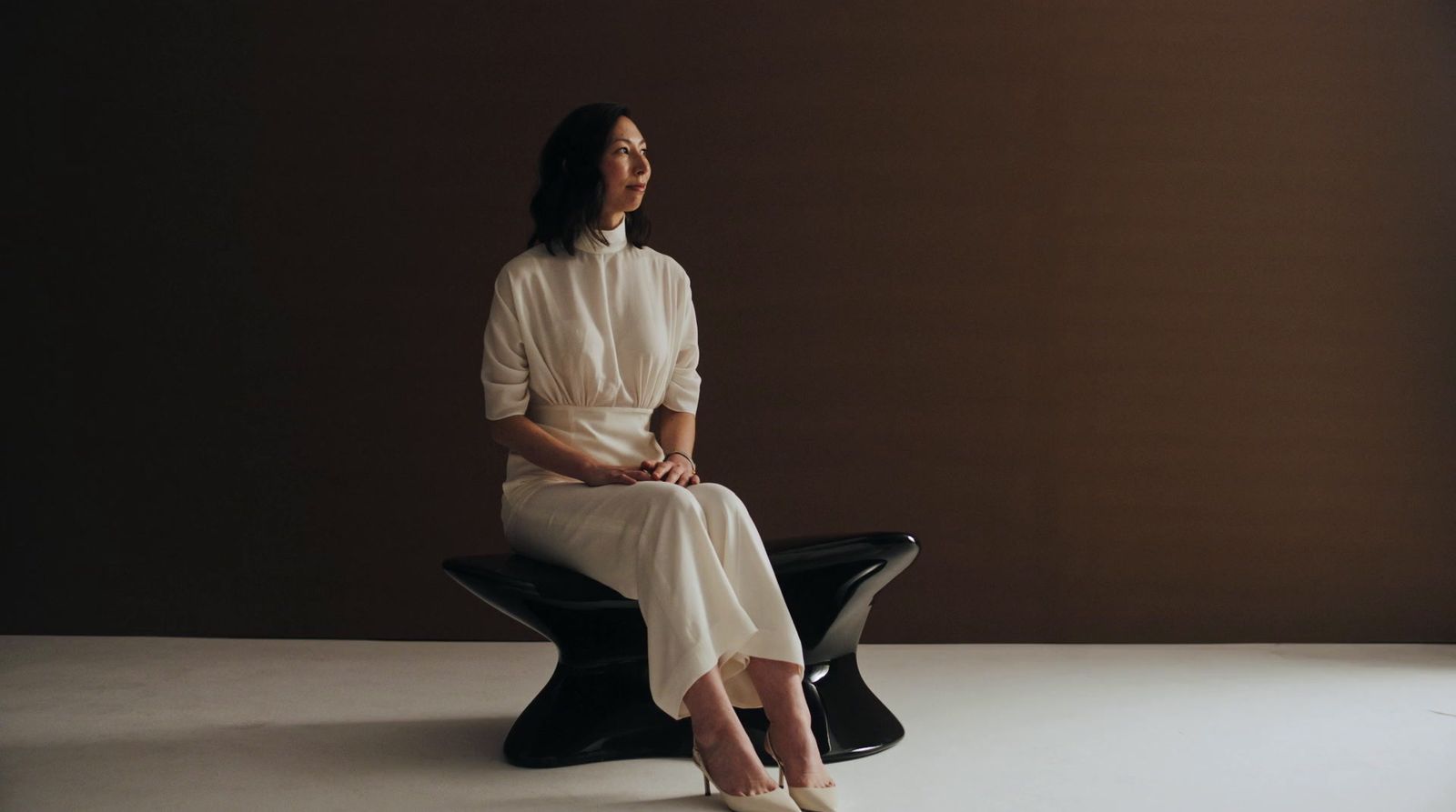 a woman in a white dress sitting on a black bench