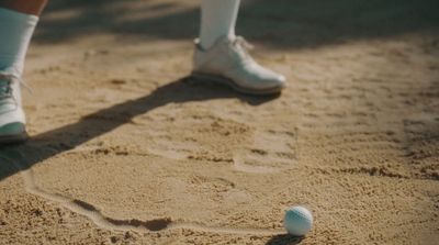 a person standing in the sand with a ball