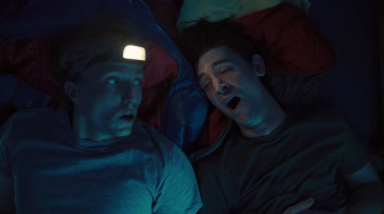 a couple of people laying in a bed with a light on their head