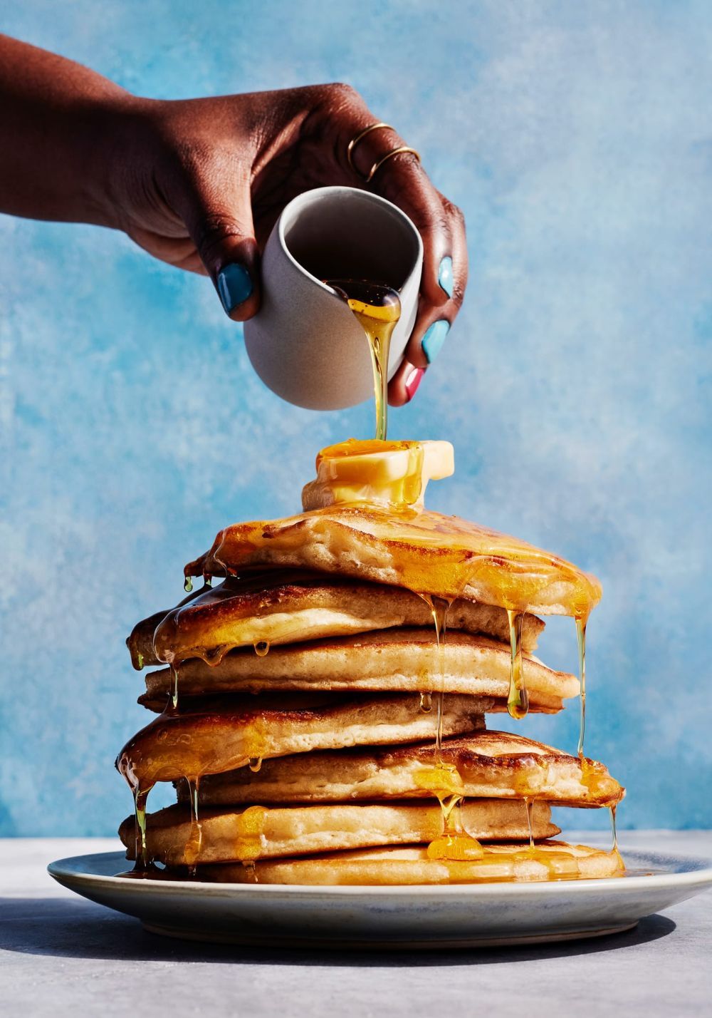 a stack of pancakes with syrup being poured on top