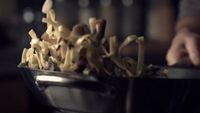 a bowl full of noodles with a hand reaching for it