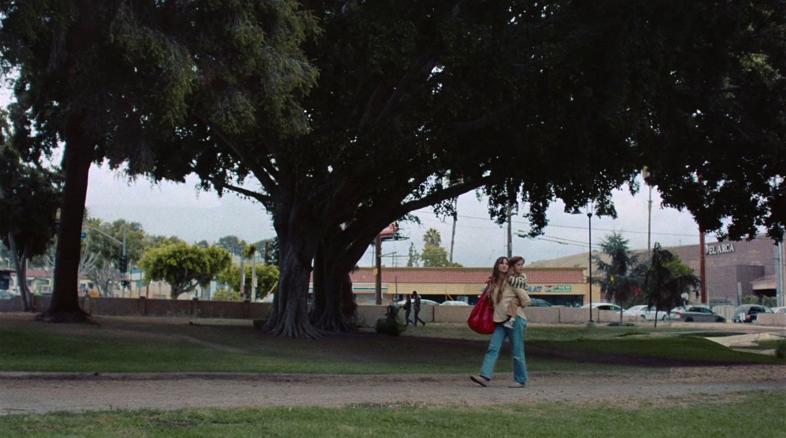 a woman walking down a street carrying a red bag