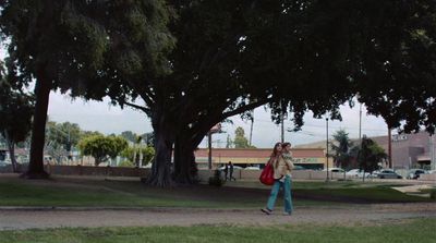a woman walking down a street carrying a red bag