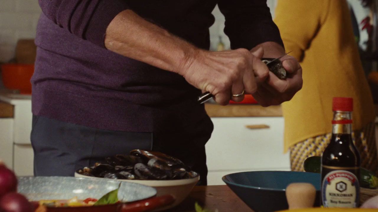 a man in a purple shirt is cutting a piece of food