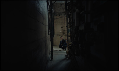 a man sitting on the ground in a dark alley