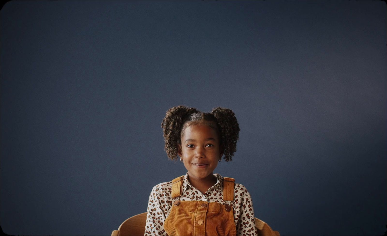 a little girl sitting at a desk with a chair