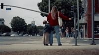 a woman standing next to a little boy on a street