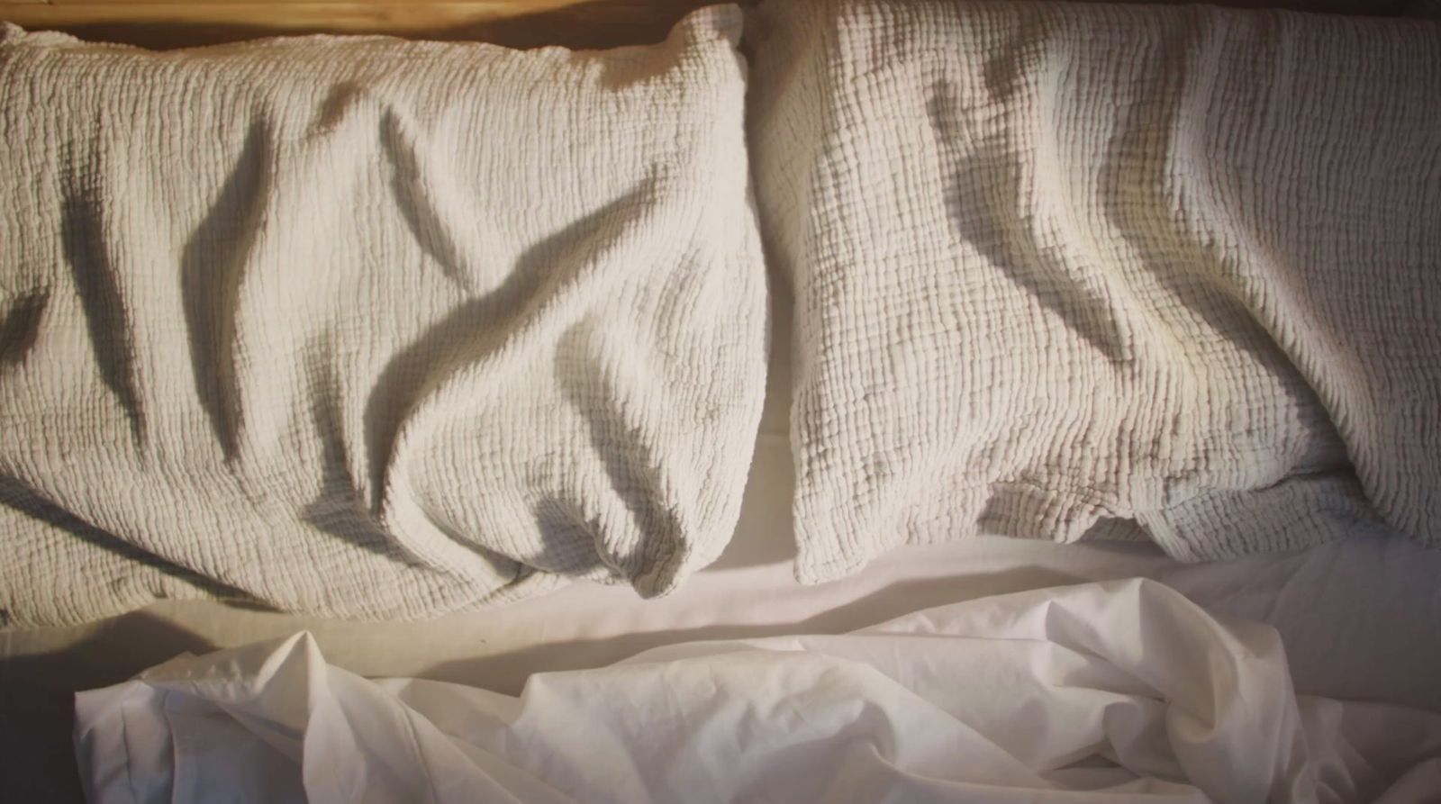 an unmade bed with white sheets and a pillow