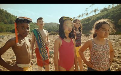 a group of kids standing on a beach next to each other