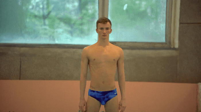 a man in a swimming suit standing in front of a window