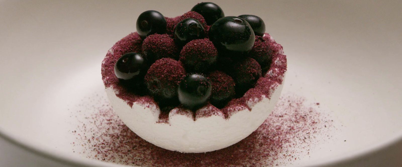 a white bowl filled with a dessert covered in berries