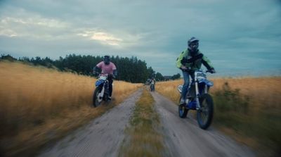 a couple of people riding bikes down a dirt road