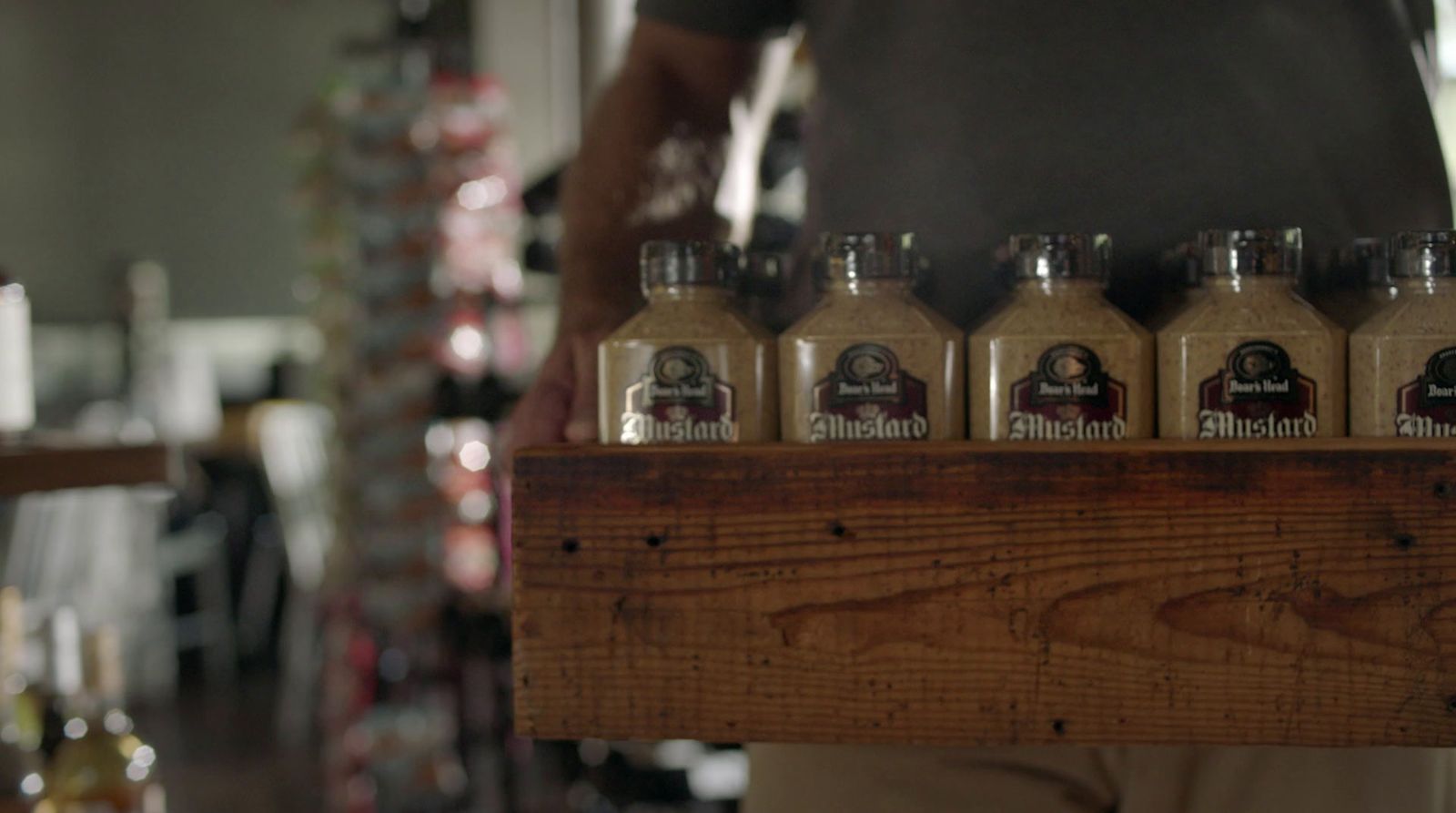 a person holding a wooden tray with six bottles of coffee