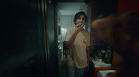 a man standing in a kitchen brushing his teeth