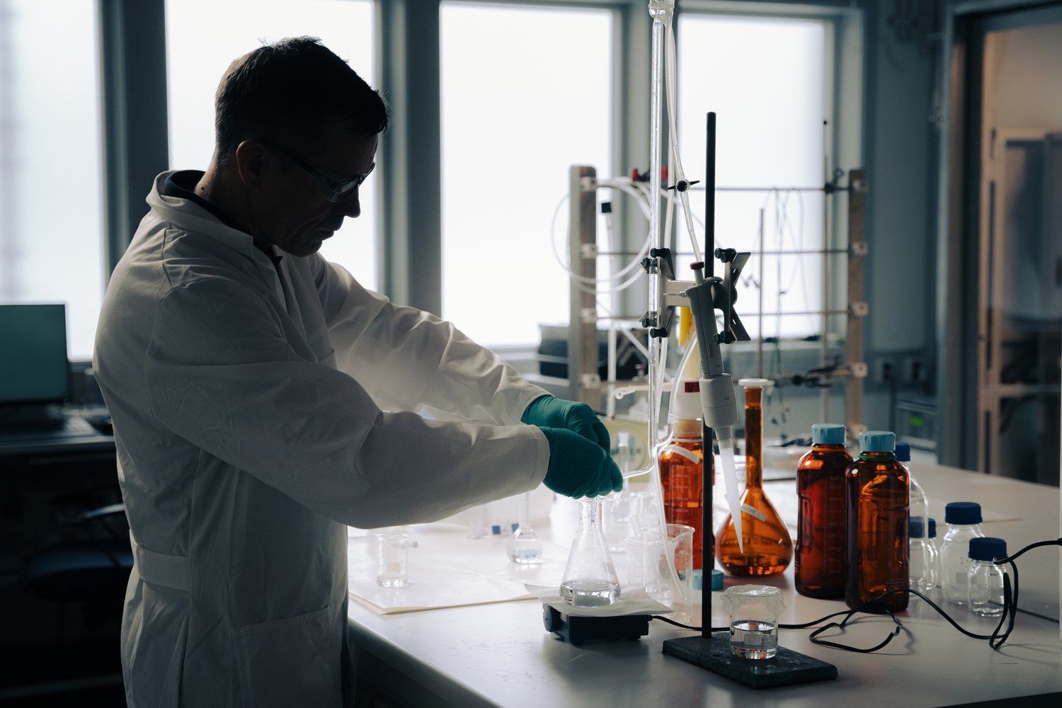 a man in a lab coat and gloves working in a lab