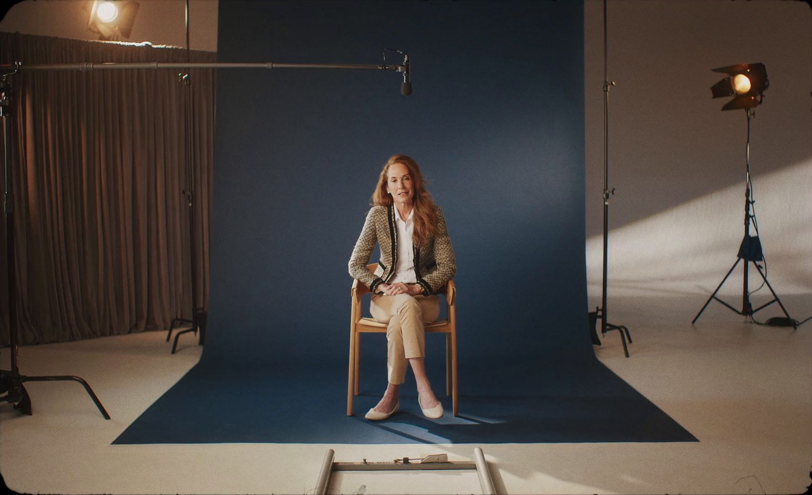 a woman sitting on a chair in front of a blue backdrop