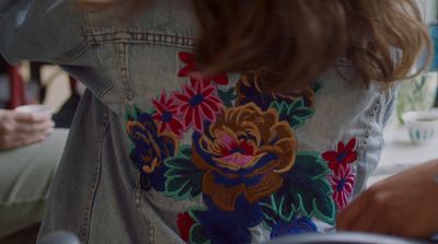 a woman wearing a jean jacket with flowers on it