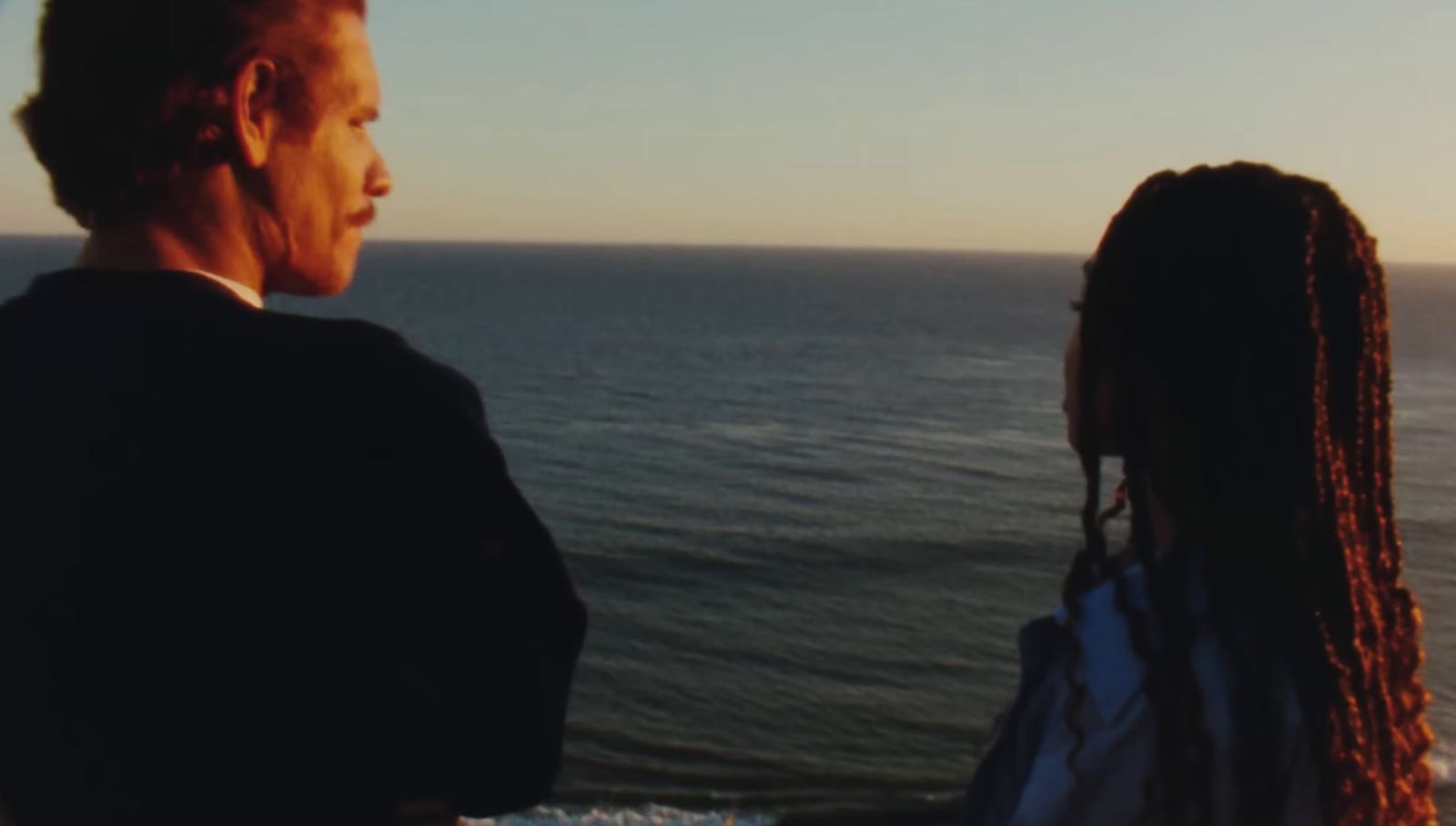 a man and a woman looking out at the ocean