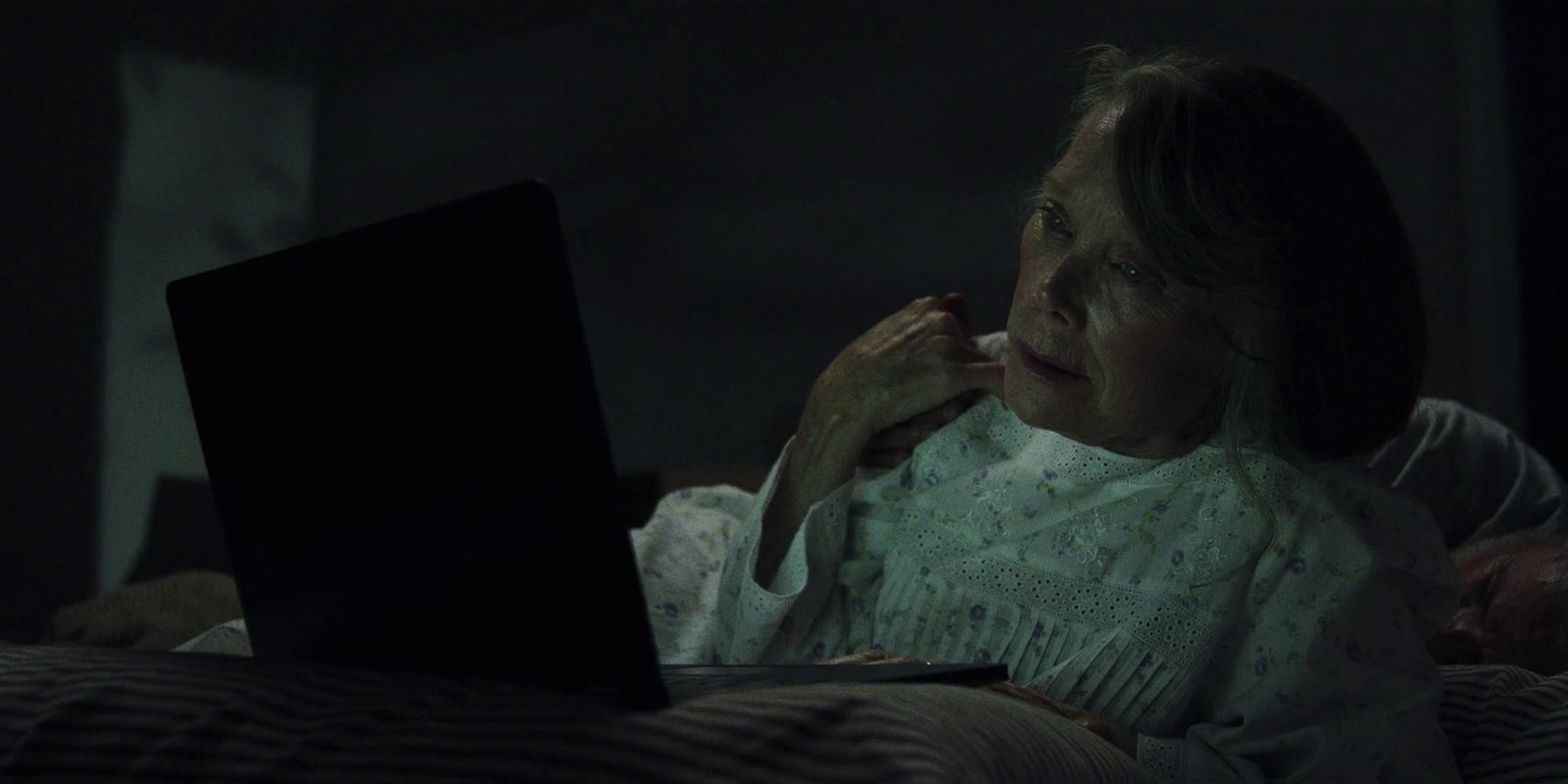 a woman sitting in bed looking at a laptop