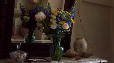 a vase of flowers sitting on a table in front of a mirror