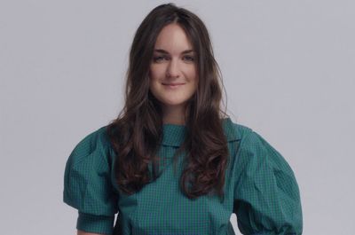 a woman in a green top smiles at the camera