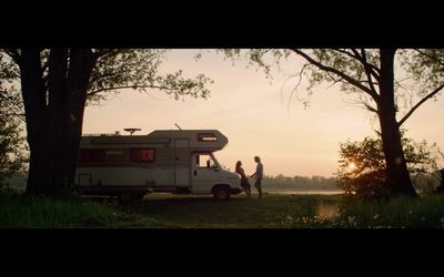 a couple of people standing next to a parked camper