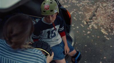 a young boy sitting on top of a skateboard next to a woman