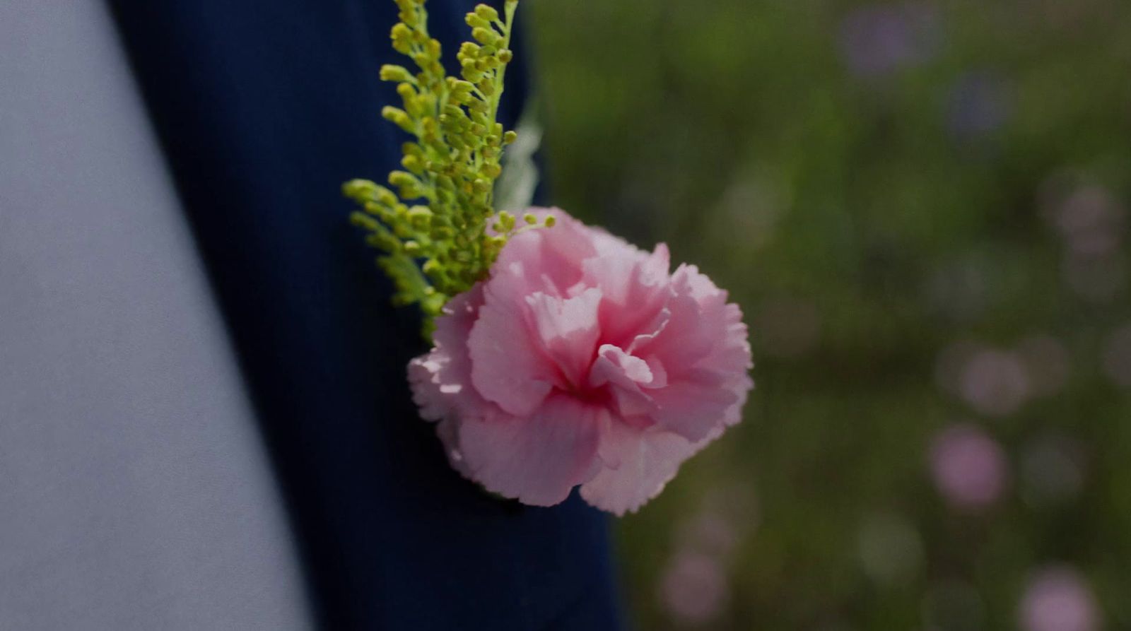 a close up of a pink flower on a man's lapel