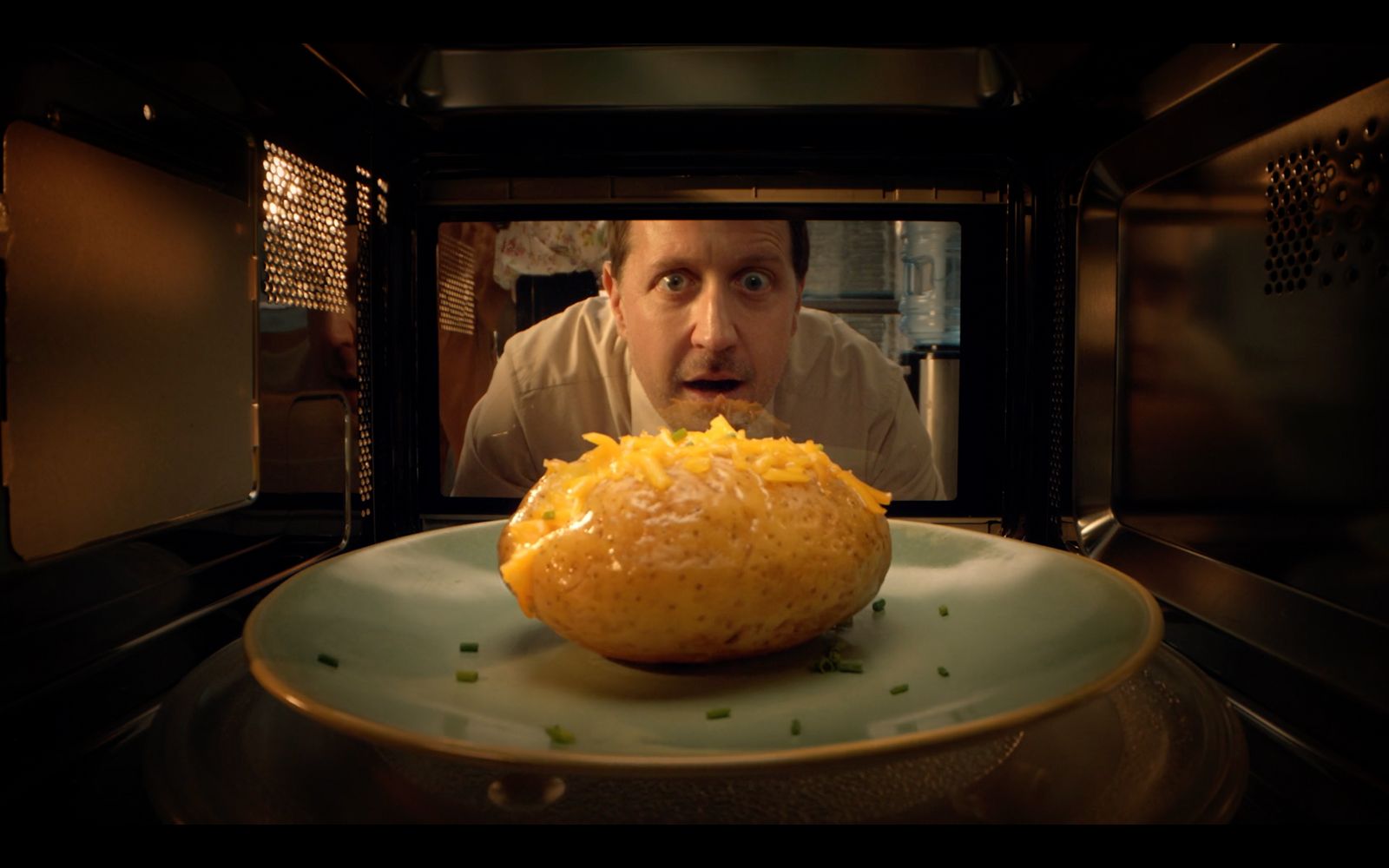 a man in a microwave with a plate of food in front of him