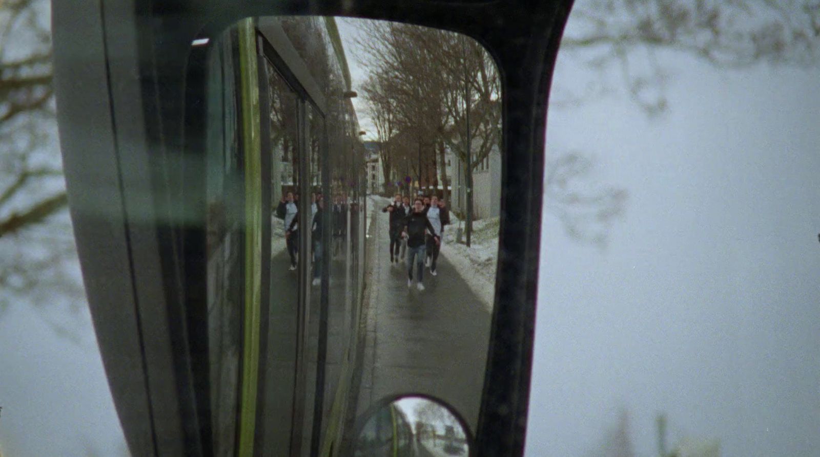 a rear view mirror on a vehicle reflecting people on the street