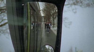 a rear view mirror on a vehicle reflecting people on the street