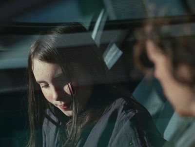 a woman sitting in a car looking at her cell phone