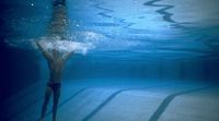 a man standing under water in a swimming pool