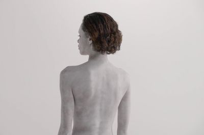 a woman with no shirt standing in front of a white wall