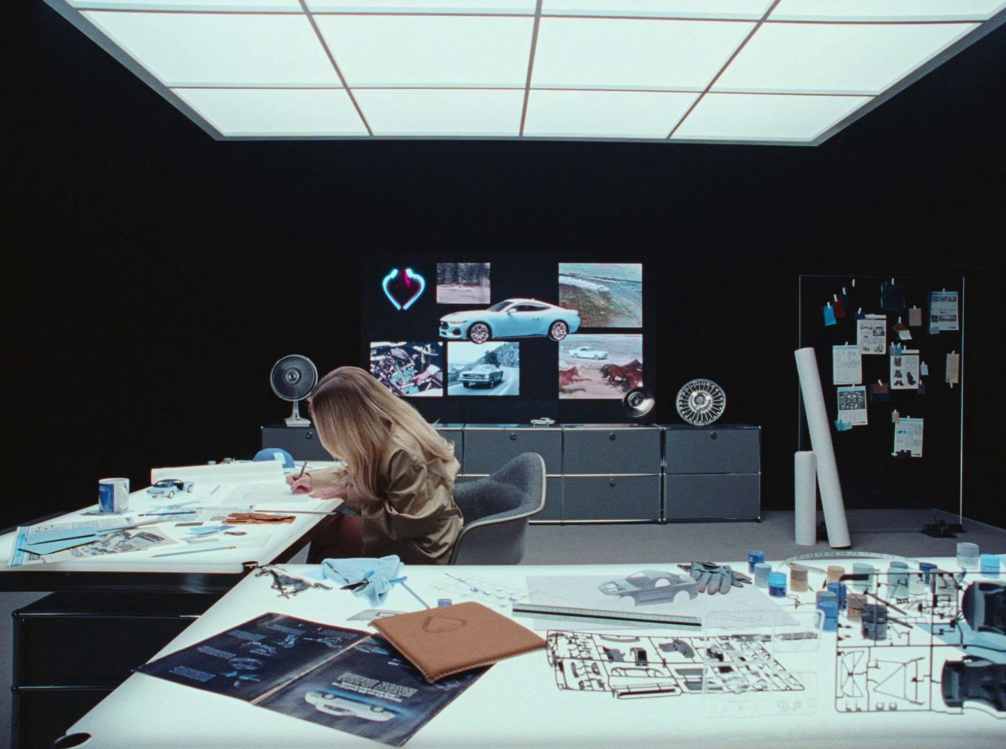 a woman sitting at a desk in front of a monitor