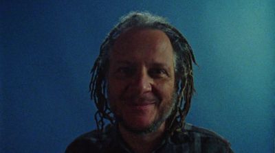 a man with dreadlocks is smiling for the camera