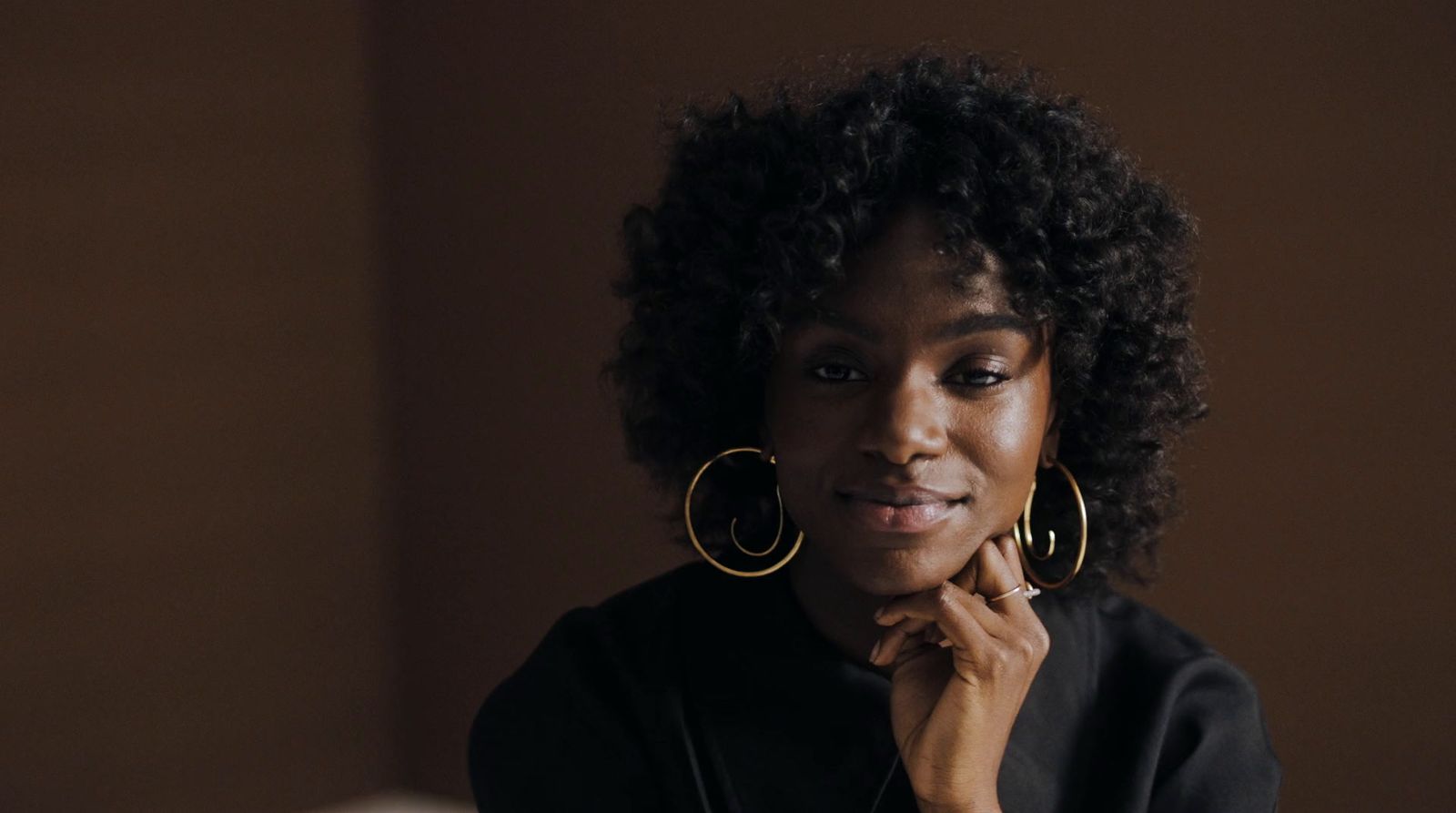 a woman wearing large gold hoop earrings and a black top