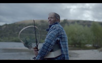 a man holding a tennis racquet on a beach