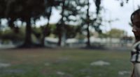 a woman standing in a park with a frisbee in her hand