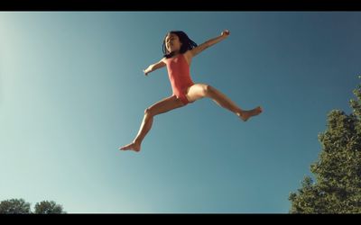 a young girl in a red swimsuit jumping in the air