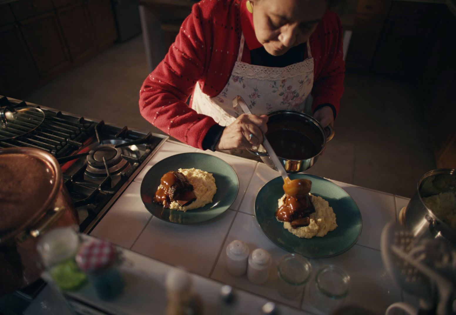 a woman in a red jacket preparing food in a kitchen