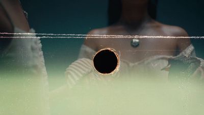 a woman standing in front of a mirror with a hole in it