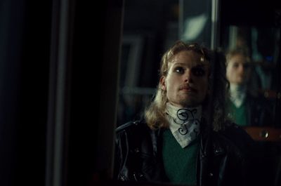 a man in a leather jacket looking at himself in a mirror