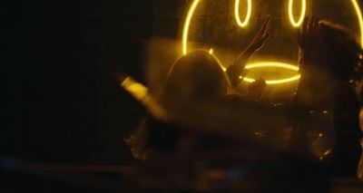 a woman sitting in front of a yellow smiley face sign
