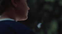 a young man in a blue shirt looking off into the distance
