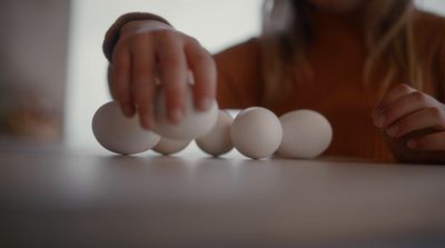 a woman is placing eggs in a row on a table